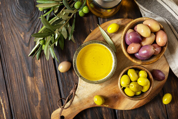 Freshly picked olives berries in wooden bowls and pressed oil served on old wooden boards. View...