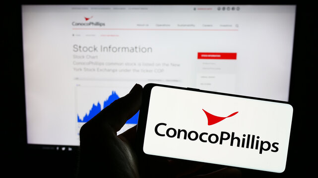 Stuttgart, Germany - 06-25-2023: Person holding mobile phone with logo of US oil and gas business ConocoPhillips Company on screen in front of web page. Focus on phone display.