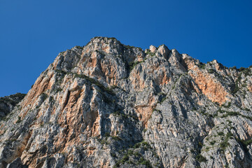 Rough rocky stones. The tops of the yellow peaks of the rocks. Red stones on a blue background. Gray rocks at high altitude. Alps top on blue sky.