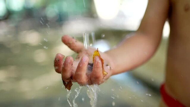 Child washing hands outside during heat day. Refreshing water during summer day. Little boy wearing bathing suit brief
