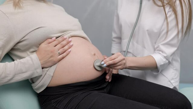 Female doctor using stethoscope examining pregnant woman in clinic. Medical exam pregnant woman
