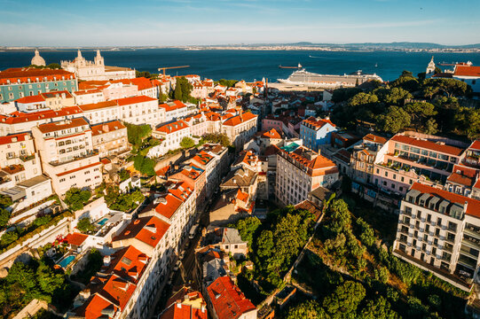 Aerial drone view of Miradouro da Graca with National Pantheon visible on far left, and large cruise ship moored on the Tagus River harbour, Lisbon, Portugal