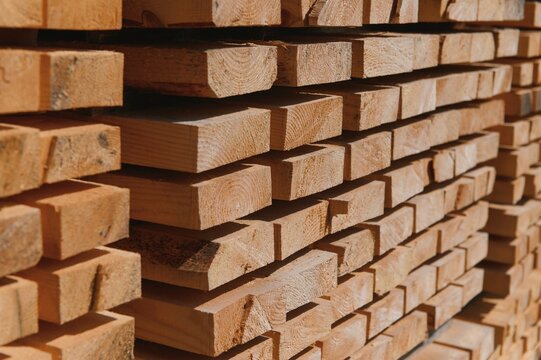 Stack of lumber of a wooden board from a tree, close-up, background. Wooden boards at the sawmill, carpentry workshop. Sawing and air drying of wood. Woodworking industry. Wooden boards