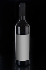 Red wine bottle close up on a black background