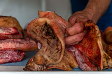 Pig's ear on the counter. The seller's hand holds the product. Close-up.