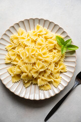 Farfalle bow cooked pasta in a plate, top view.
