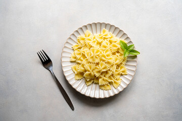 Farfalle bow cooked pasta in a plate, top view.