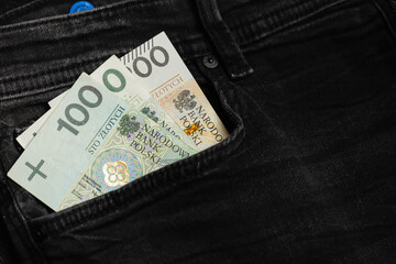 warsaw, poland - 05 07 2023: Polish banknotes of PLN protruding from the pocket of black pants (selective sharpness)