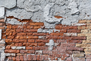 Plaster peeling from an old red brick wall. Worn out building in Venice.