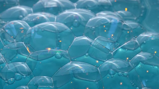 Texture of soap bubbles in close up. Bubble bath. Gel for washing or washing hands.Blue background with bursting bubbles