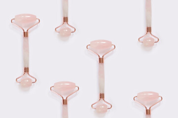 Creative pattern from the facial massage set for home spa. Facial roller made of rose quartz on a light background. The concept of natural treatment