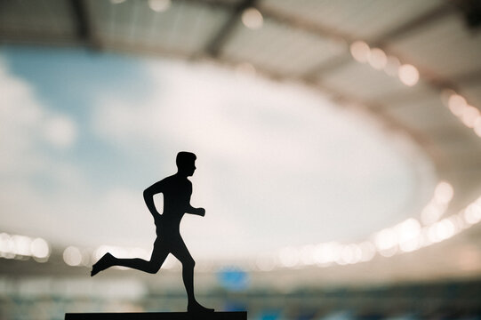 Silhouette of a Male Athlete, an Endurance Runner, Thriving under the Enchanting Evening Light of a Modern Sports Stadium