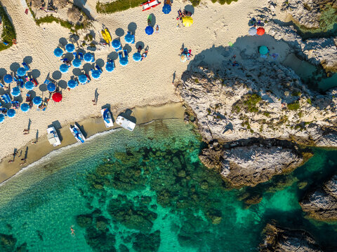Italy, July 2023: aerial view from the drone of a crystalline Caribbean sea with bathers and beach umbrellas at Grotticelle locality near Capo Vaticano, Tropea, Calabria