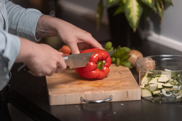 Chef cutting red pepper fruit, preparing a healthy meal in the home.