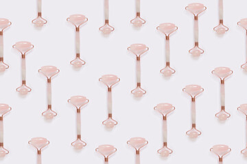 Creative pattern from the facial massage set for home spa. Facial roller made of rose quartz on a light background. The concept of natural treatment