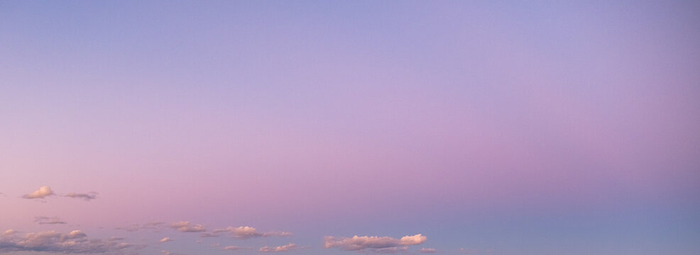 Pink and blue sky with sparse clouds at sunrise or sunset shot at 24 mm focal length