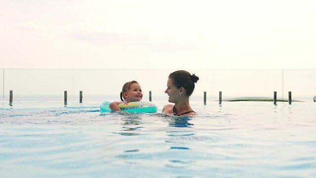 little girl and her mother are resting in outdoor swimming pool of of luxury resort, family weekend 