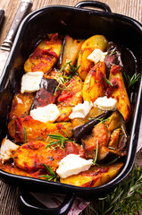 Traditional Greek briam with potato, eggplant feta cheese served as close-up in a backing pan