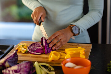 Mid section of biracial woman chopping vegetables in kitchen
