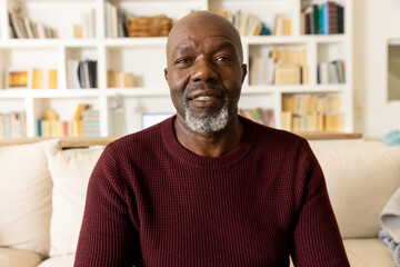 Happy senior african american man making video call smiling to camera in living room