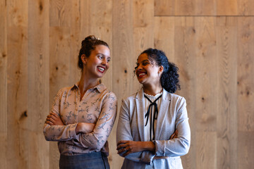 Portrait of happy diverse casual businesswomen against wooden wall in office