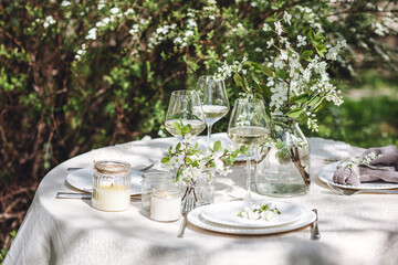 Rustic elegant eco friendly zero waste trendy wedding reception table decor with fresh spring apple cherry flowers in bloom. Beautiful marriage decoration, holiday event outdoors in the family garden