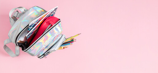Backpack with school supplies for study isolated on pink background. Back to school concept. Full school backpack. Flat lay, top view
