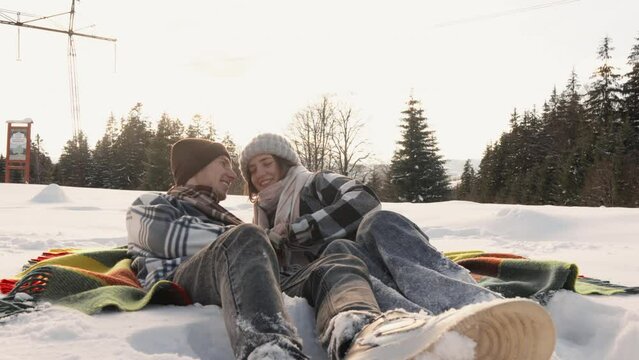 A cheerful couple shows that true love does not depend on the season, but the winter landscape makes it special. People lying in the snow, taking a break from a day's walk