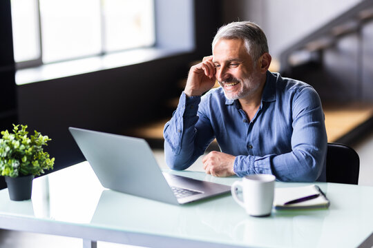 Confident Middle Aged Man Using Laptop And Having Video Call While Working From Home. Home Office.