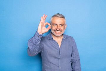 Naklejka premium Middle age man standing over blue background doing happy thumbs up gesture with hand.