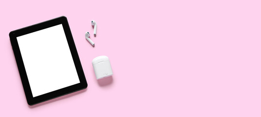 Modern tablet computer and wireless earphones on pink background with space for text