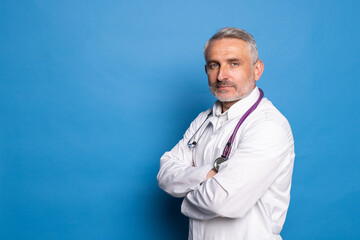 Portrait of smiling mature doctor isolated on blue background