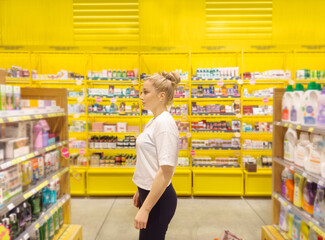 Woman buying make up at cosmetics section in store. choosing cosmetics, perfumes, creams and shampoos, Using tester.