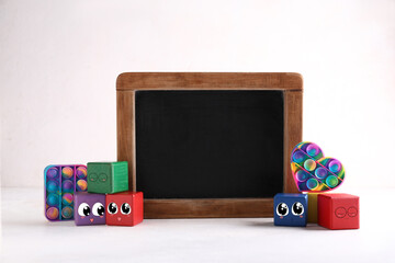 Empty chalkboard, toys and cubes with drawn cute faces on white background - obrazy, fototapety, plakaty