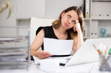 Portrait of tired woman office worker sitting at table during her workday.