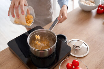 Young woman boiling pasta in kitchen, closeup