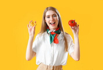 Young woman with raw pasta and tomato on yellow background