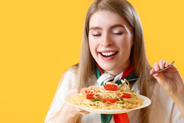 Young woman with tasty pasta on yellow background, closeup