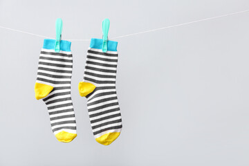 Pair of cotton socks hanging on rope against grey background