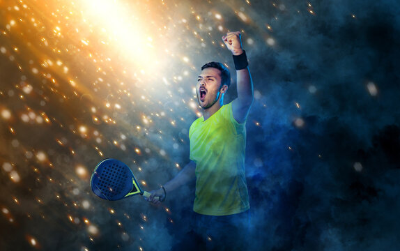 Padel tennis player celebrates victory in the game. Man athlete with paddle tenis racket on background with sparks and fire. Sport concept. Download a high quality photo for sports website.