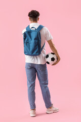 Male student with backpack and soccer ball on pink background, back view