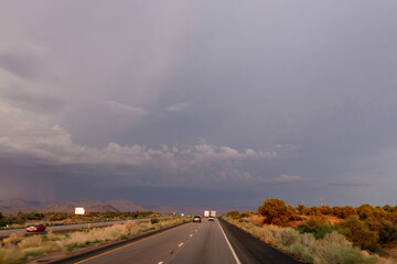 A beautiful asphalt road among hills with dry grass. A scenic landscape with highway, mountains on background and blue sky with fluffy clouds on sunny day. Phoenix, AZ, USA - 7-22-2021