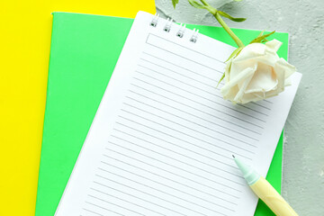 Different notebooks and rose flower on grunge background