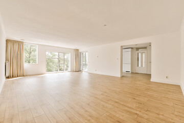 an empty living room with wood flooring and large windows looking out onto the trees in the distance are two doors