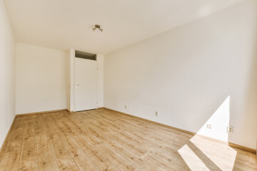 an empty room with white walls and wood flooring on the right side, there is a door in the corner to the left