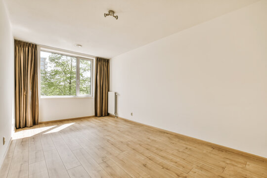 an empty living room with wood floor and large window overlooking the trees in the distance is bright white paint on the walls
