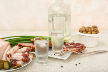 Shots with cold vodka and snacks on light background