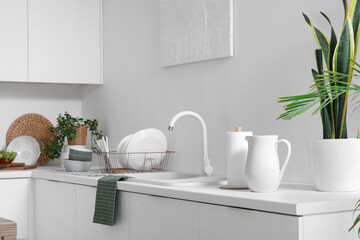 Fototapeta na wymiar White counters with sink, utensils and houseplants in modern kitchen