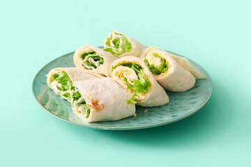 Plate of tasty lavash rolls with egg and greens on turquoise background