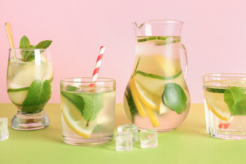Glasses and jug of lemonade with cucumber on green table